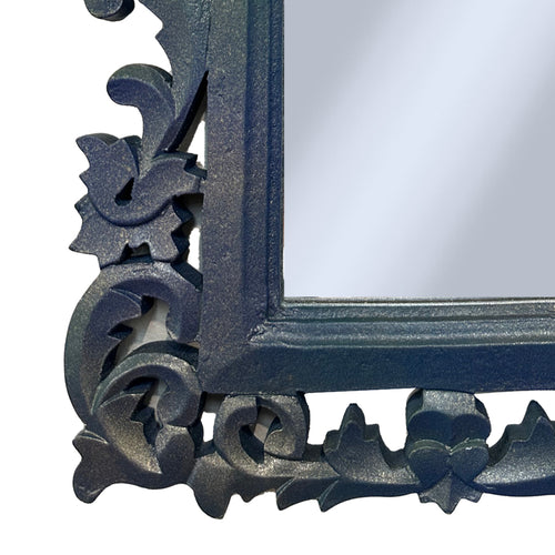 Decorative corner detail of mirror with intricate black frame on a white background
